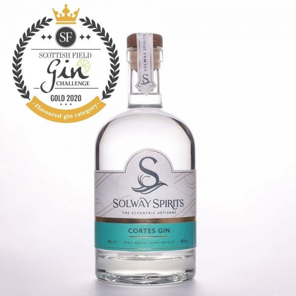 A clear glass bottle of Solway Spirts Cortes Gin. The bottle features a white, turquoise blue, and gold label and wooden stopper.