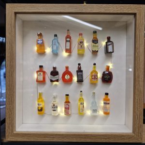 Picture frame with miniature bottles of alcohol lit up with fairy lights